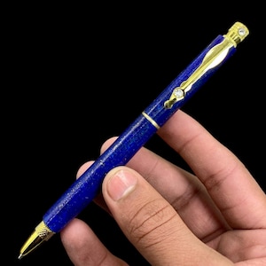 Op de afbeelding: Een blauwe en gouden pen met een lapis lazuli-lichaam en gouden accenten. De pen heeft een diamantvormig detail aan de bovenkant.