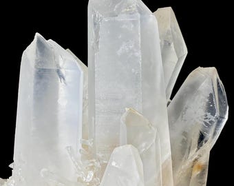 May include: Close-up of a cluster of clear quartz crystals. The crystals are translucent with sharp, pointed terminations. The quartz has a slightly frosted appearance and sits against a black background. The overall effect is one of natural beauty and geological interest.