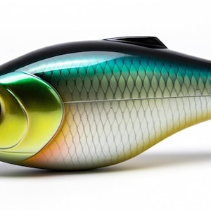Könnte beinhalten: Ein detaillierter, fischförmiger Angelköder mit Metallic-Finish. Der Köder hat eine schwarze Oberseite, die in Türkis und Grün übergeht, mit einem gelb-orangen Kopf und einem silbernen Unterbauch. Das Auge ist leuchtend orange.