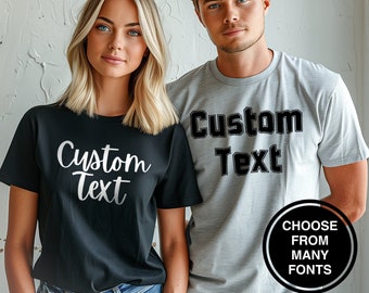 May include: Two people wearing black and gray t-shirts with the text "Custom Text" in different fonts. The text is in white on the black shirt and black on the gray shirt.  Choose from many fonts.