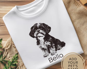 May include: White t-shirt with a black and white illustration of a Shih Tzu dog. The text "Bella" is printed below the dog. The text "ADD YOUR PET'S NAME" is printed in a circle on the bottom right corner of the shirt.