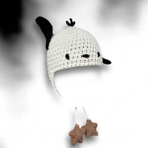 Pode incluir: Chap&eacute;u branco de croch&ecirc; com orelhas pretas e enfeites em forma de estrela marrom. O chap&eacute;u tem a forma de um personagem de desenho animado com um rosto simples.