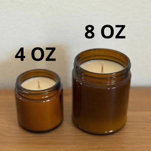two brown glass jars, one larger and one smaller, placed on a wooden surface. Above the jars, there are two black text labels indicating the size of the jars: "4 OZ" and "8 OZ".