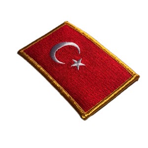 Puede incluir: Parche bordado con la bandera de Turquía. El parche rectangular tiene un fondo rojo con una luna creciente y una estrella blancas. El borde es dorado. Ideal para chaquetas, bolsos u otros artículos de tela.