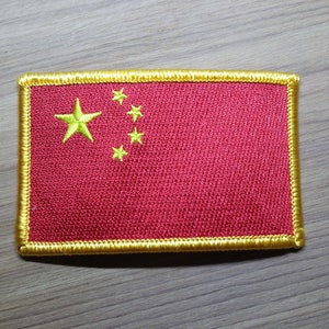 Op de afbeelding: Een rood geborduurd patch met een gele rand en vijf gele sterren. De patch is een weergave van de Chinese vlag.