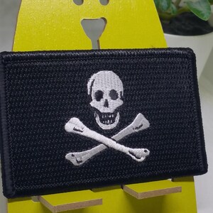 May include: A black embroidered patch with a white skull and crossbones design.