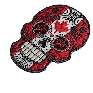Könnte beinhalten: Gestickter Totenkopf-Aufnäher in Rot und Weiß mit kanadischem Ahornblatt und Sternen. Das Design umfasst florale Muster und einen schwarzen Rand. Ideal zum Anpassen von Jacken, Taschen oder anderen Stoffartikeln. Der Aufnäher ist ca. 10 cm breit.