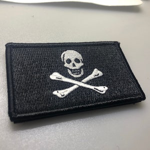 May include: A black embroidered patch with a white skull and crossbones design.