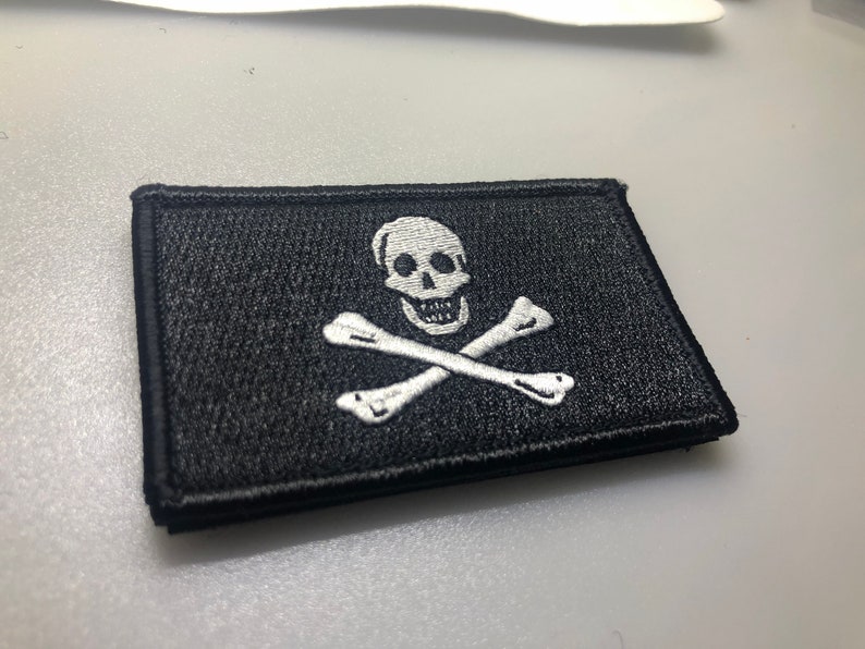 May include: A black embroidered patch with a white skull and crossbones design.