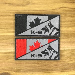 以下が含まれることがあります： カナダ国旗のデザインが施された長方形のパッチ2枚。黒いカエデの葉とジャーマンシェパード犬のシルエットが特徴です。「K-9」の文字がカエデの葉と犬の下に印刷されています。1つのパッチは赤い旗、もう1つは黒です。