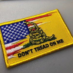 May include: A yellow embroidered patch featuring a coiled rattlesnake and the words "Don't Tread On Me", with a stylised American flag.