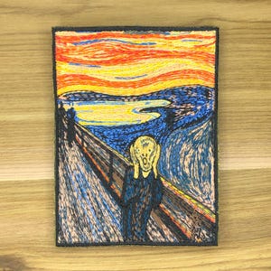 May include: Embroidered patch depicting Edvard Munch's "The Scream". The artwork shows a figure with hands on its face against a swirling sky in orange, yellow, and blue. The patch has a black border and is rectangular.
