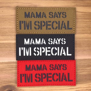May include: Three rectangular patches in tan, black, and red, each with the text "MAMA SAYS I'M SPECIAL" in a bold, stencil-style font. The patches are made of a textured fabric and are stacked vertically.