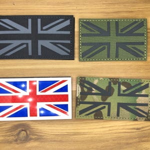 May include: Four rectangular patches displaying the Union Jack flag. The patches are in different colors: black, green, and camouflage. One is a reflective sticker with red, white, and blue. Ideal for clothing or accessories.