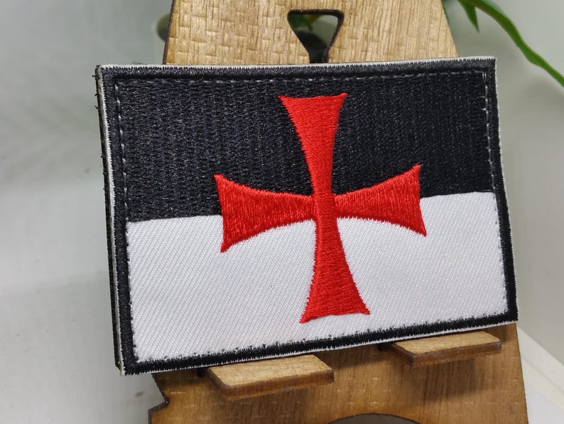 Puede incluir: Un parche bordado en blanco y negro con una cruz roja. El parche es una representaci&oacute;n de los Caballeros Templarios.