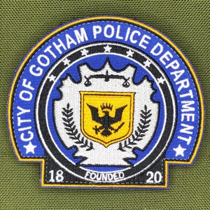以下が含まれることがあります： 青と白で「CITY OF GOTHAM POLICE DEPARTMENT」の文字が刺繍されたパッチ。パッチには、黄色の盾と黒い鳥が描かれた中央のエンブレムと、「FOUNDED 1820」の文字が含まれています。