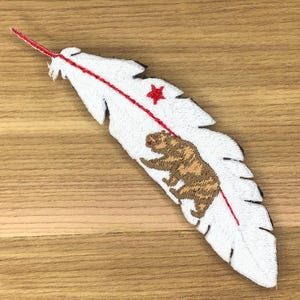 May include: Embroidered white feather patch with a red star and a brown bear, and a red line down the centre. The patch has a California theme.