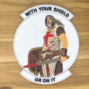 May include: Embroidered patch featuring a medieval knight with a red cross on his tunic, holding a sword and shield. The patch is circular with the text "WITH YOUR SHIELD OR ON IT" in a white banner.