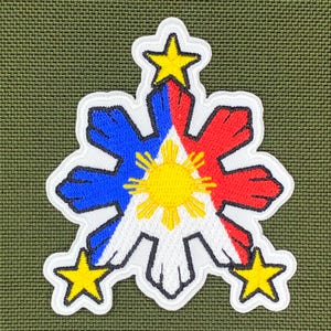 Pode incluir: Patch bordado com o emblema da bandeira filipina. O design inclui um sol amarelo central, secções vermelhas e azuis e três estrelas amarelas. O patch é contornado em branco e colocado sobre um fundo verde texturizado.