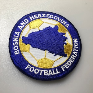 Könnte beinhalten: Ein blauer und weißer gestickter Aufnäher mit dem Text "Bosnien und Herzegowina Fußballverband" und einem Fußball mit einer blauen Umrandung der Landkarte.