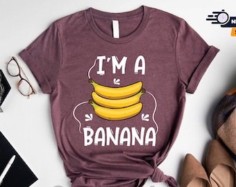 May include: A heather maroon t-shirt with the text "I'M A BANANA" in white. The text is surrounded by a graphic of three yellow bananas.