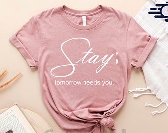 May include: A heather mauve t-shirt with the text "Stay; tomorrow needs you." printed in white.