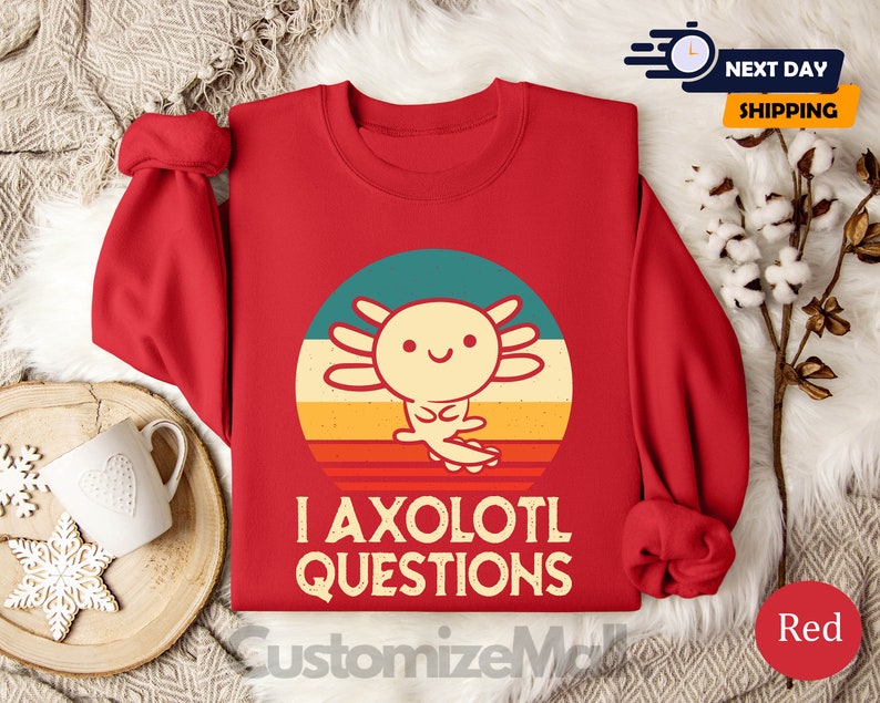 May include: Red sweatshirt featuring a retro-style graphic of an axolotl and the text "I axolotl questions".