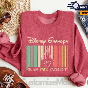 a pink sweatshirt with a Disney Grandpa design, a pair of brown shoes, sunglasses, and a woven basket.
