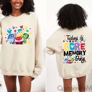May include: A beige sweatshirt with a graphic of the characters from the movie Inside Out, including Joy, Sadness, Anger, Fear, and Disgust. The back of the sweatshirt has the text "Today is a CORE MEMORY Day" with a Mickey Mouse head in the middle of the word "CORE".
