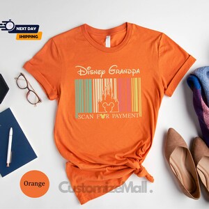a collection of items, including a t-shirt with a Disney Grandda design, a pair of shoes, a notebook, a pen, a watch, a potted plant, and a scarf. The items are arranged on a white background, creating a visually appealing and organized display.