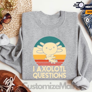 May include: Grey sweatshirt featuring a retro-style graphic of an axolotl with the text "I axolotl questions".