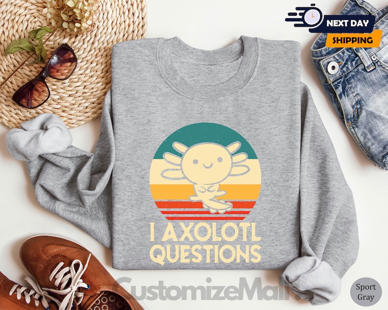 May include: Grey sweatshirt featuring a retro-style graphic of an axolotl with the text "I axolotl questions".