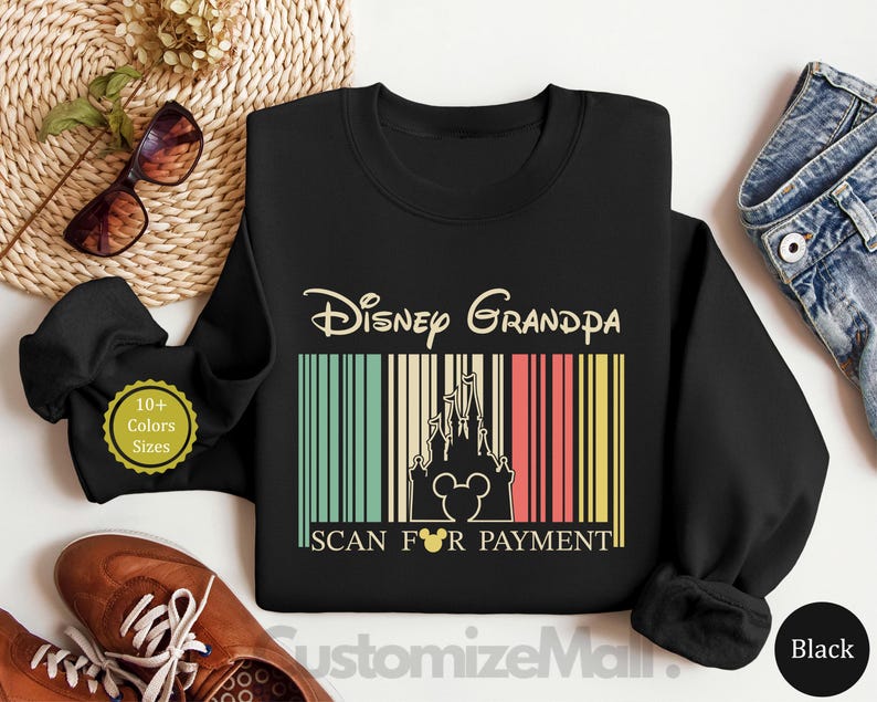 a black sweatshirt with a Disney Grandpa design, a pair of sunglasses, a pair of brown shoes, and a pair of jeans, all laid out on a white background.