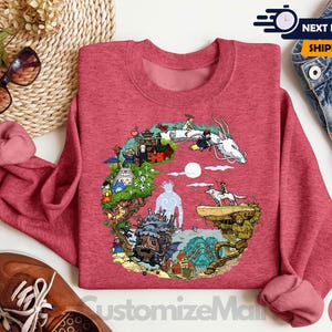 a red sweatshirt with a colorful illustration of a dragon, a castle, and various other elements, along with a pair of jeans and a pair of sunglasses.
