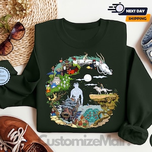 a green sweatshirt with a colorful illustration of a dragon, a castle, and various other fantastical elements, along with a pair of sunglasses and a pair of jeans.