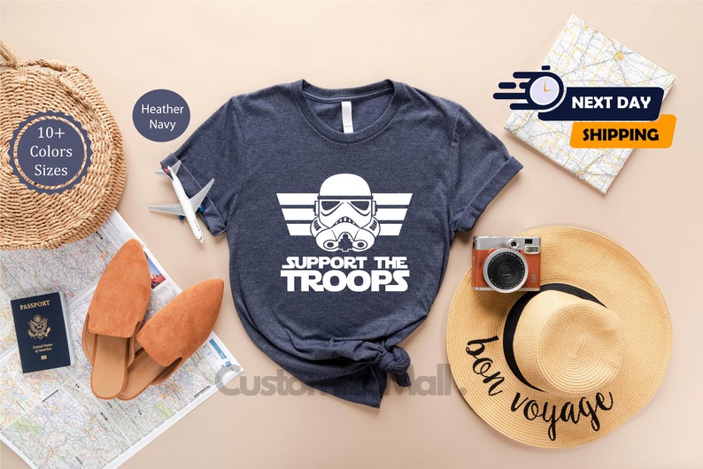 May include: A navy blue t-shirt with a white graphic of a Star Wars Stormtrooper helmet with wings and the text "Support the Troops".