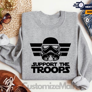 May include: Gray sweatshirt with a black and white graphic of a Star Wars Stormtrooper helmet with the text "Support the Troops".