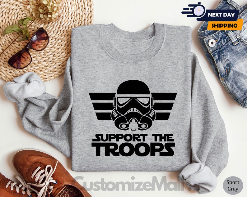 May include: Gray sweatshirt with a black and white graphic of a Star Wars Stormtrooper helmet with the text "Support the Troops".