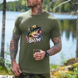 May include: Olive green t-shirt featuring a cartoon bass wearing a camouflage hat and gold chain, with the word "BRUH!" in white. The shirt is made of a soft material.