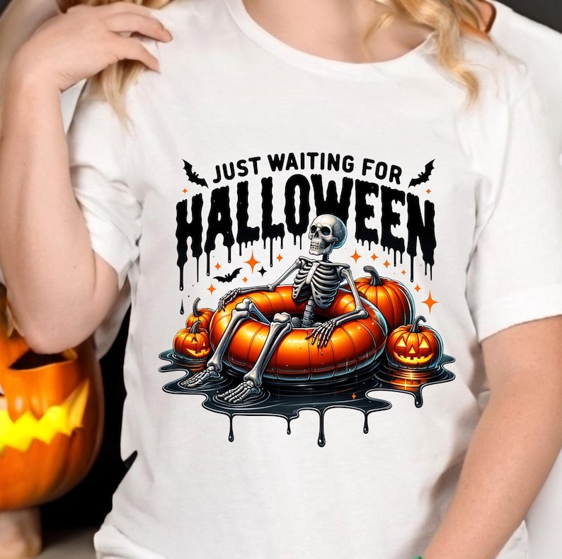 May include: White t-shirt with a graphic of a skeleton in a pumpkin-shaped pool float. The text "Just Waiting for Halloween" is above the skeleton.