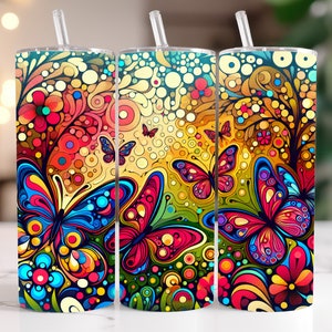Puede incluir: Tres vasos de sublimación coloridos con un diseño psicodélico de mariposa y flores. Los vasos son una mezcla vibrante de rojo, naranja, amarillo, verde, azul y morado.