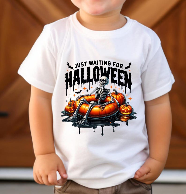 May include: White t-shirt with a skeleton wearing a pumpkin float and the text "Just Waiting for Halloween".