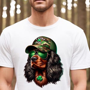 May include: White t-shirt with a cartoon image of a brown and black dog wearing a camouflage baseball cap with the text "Lucky Dog" and green shamrocks. The dog is wearing green sunglasses and has a green shamrock around its neck.