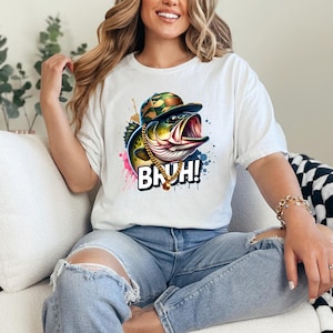 May include: White t-shirt featuring a colorful graphic of a bass wearing a camouflage hat and gold chain, with the word "BRUH!" in bold letters. The design includes splashes of pink, blue, and yellow.