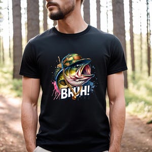 May include: Black t-shirt featuring a cartoon fish wearing a camouflage hat and gold chain. The fish has an open mouth and the word "BRUH!" is printed in white. The design includes colorful paint splatters.
