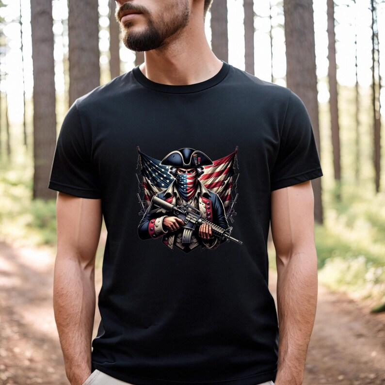 May include: A black t-shirt with a graphic of a man dressed as a revolutionary soldier holding a rifle. The soldier is wearing a bandana over his face, and the American flag is behind him.