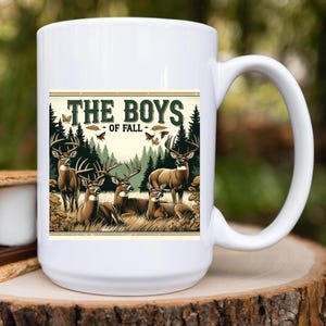 K&ouml;nnte beinhalten: Wei&szlig;e Keramiktasse mit einer Grafik von f&uuml;nf Hirschen in einer Waldlandschaft. Der Text "The Boys - Of Fall" ist auf die Tasse gedruckt.