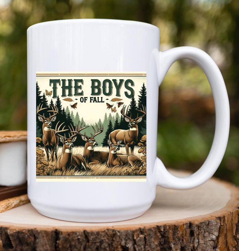 K&ouml;nnte beinhalten: Wei&szlig;e Keramiktasse mit einer Grafik von f&uuml;nf Hirschen in einer Waldlandschaft. Der Text "The Boys - Of Fall" ist auf die Tasse gedruckt.