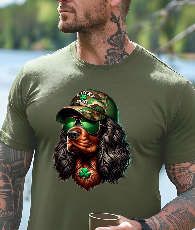 May include: A green t-shirt with a cartoon image of a brown and black dog wearing a camouflage baseball cap with the text "Lucky Dog" and green sunglasses. The dog is wearing a green shamrock around its neck.