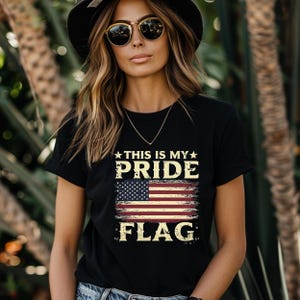 Puede incluir: Una camiseta negra con un gr&aacute;fico de bandera estadounidense desgastado y el texto "This is my pride flag".
